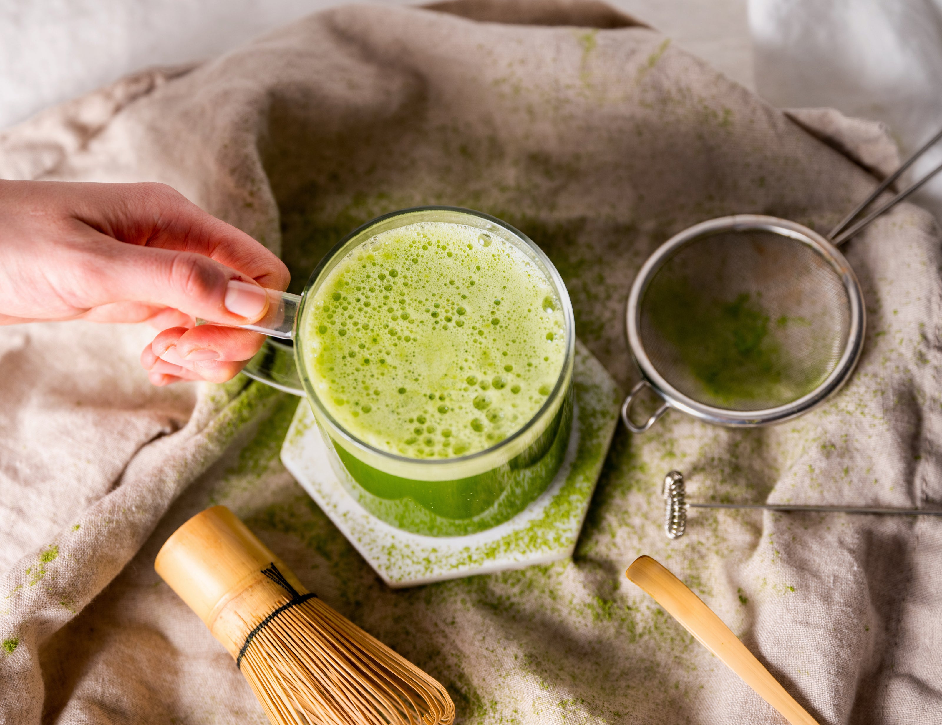 A hand holds a cup of Organic Match Tea